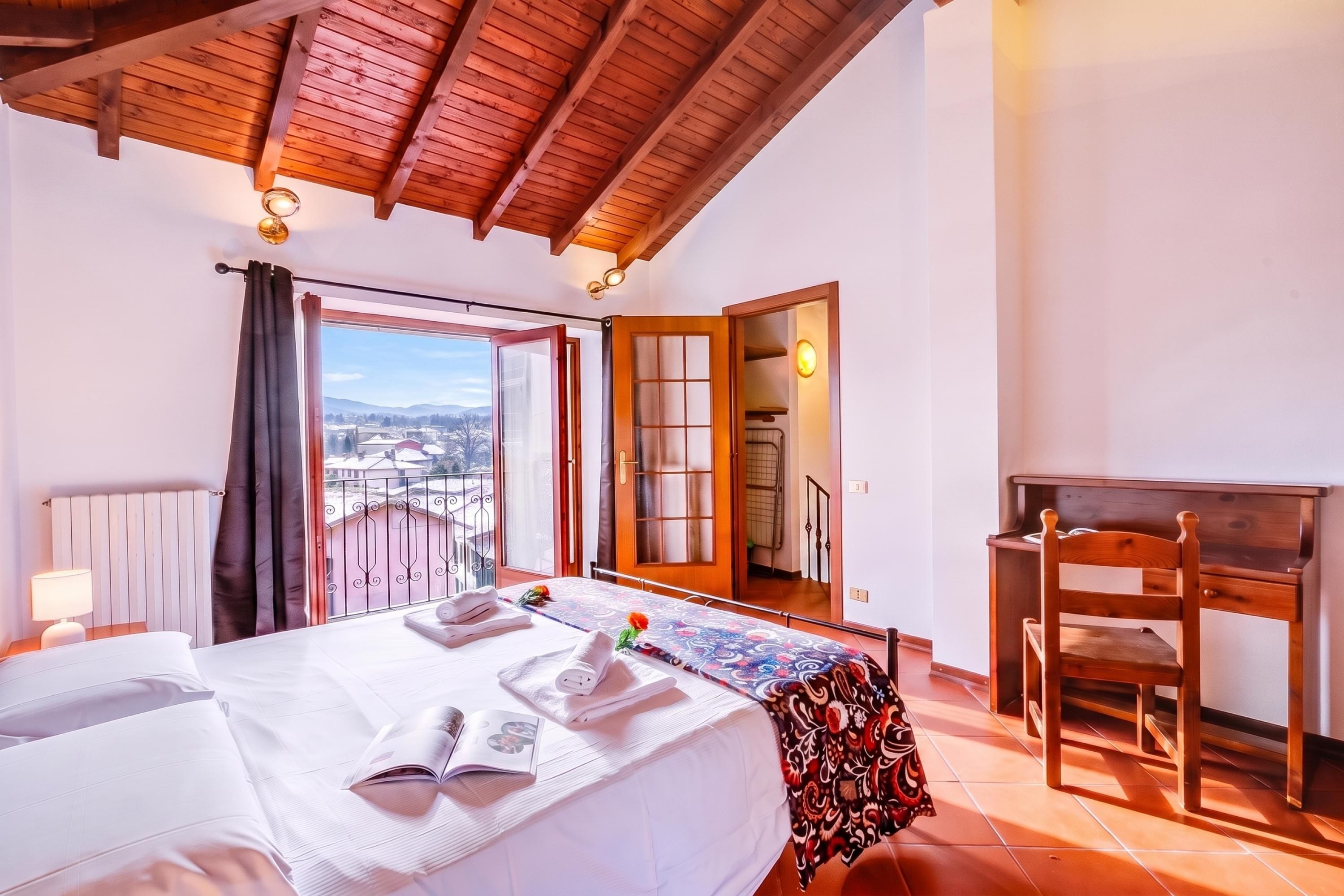 Una camera da letto con un letto, una scrivania e una sedia. Si vede una finestra con vista sull'esterno.