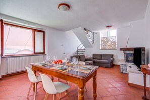 A dining area with a wooden table set for four, a sofa, and a fireplace. - Casa al Castello in Leggiuno With Garden (Leggiuno)