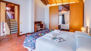 A bedroom with a bed, a desk, and a staircase leading to another room. - Casa al Castello in Leggiuno With Garden (Leggiuno)