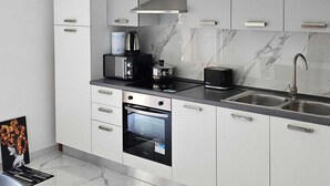 A modern kitchen with white cabinets, a built-in oven, a microwave, a kettle, and a sink. - Modern Hillside Retreat with Panoramic Views & Private Balcony with AC (Mussomeli)