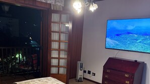 Une chambre à coucher avec un lit, une commode, un téléviseur et une fenêtre donnant sur un paysage agréable.