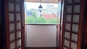 Une porte en bois avec des panneaux de verre donnant sur un balcon dont le sol est recouvert de carreaux.