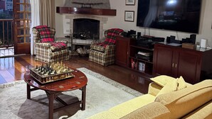 Un salon chaleureux avec une cheminée, un grand téléviseur à écran plat et des fauteuils confortables.