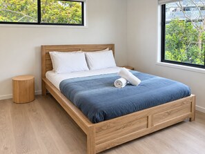 A single-bed room with a wooden frame, white bedding, and a blue bedspread. - Luxe Living in GC – Your Stylish Escape (Mermaid Waters)
