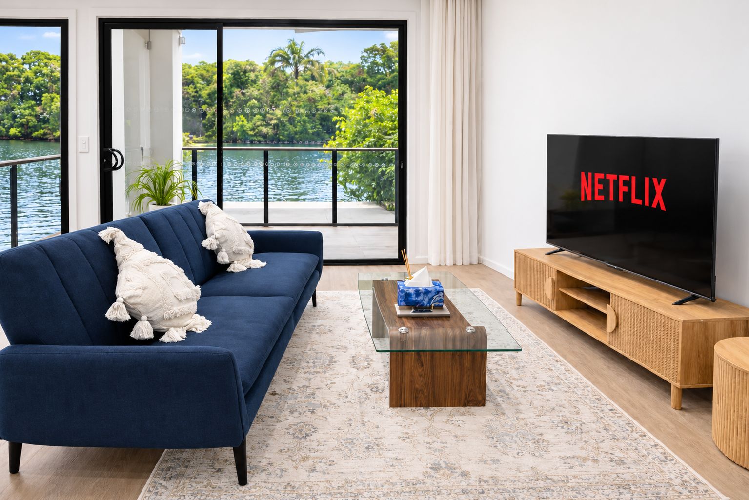 A living room with a sofa, a coffee table, a TV, and a view of a lake.