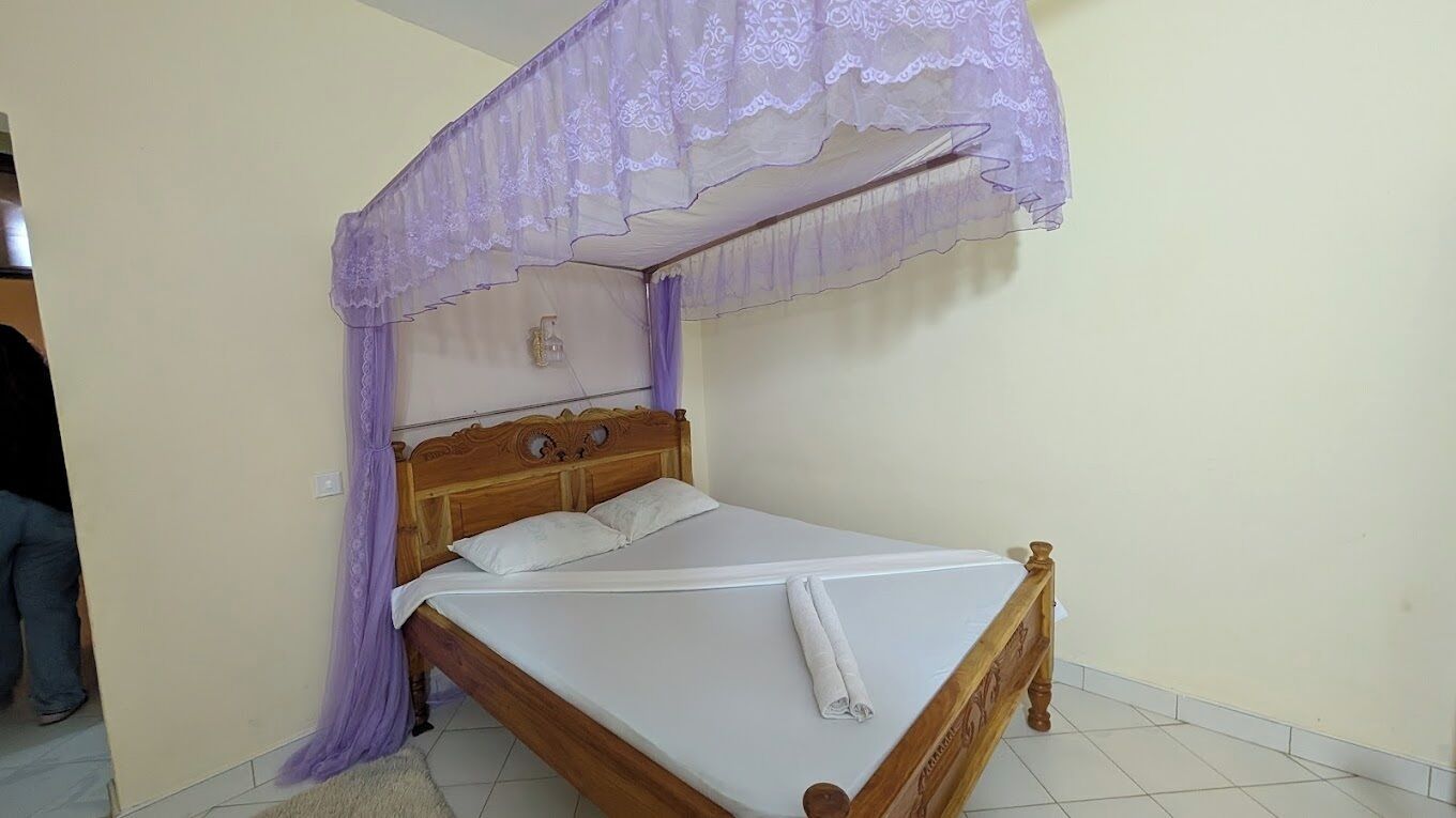 Un letto singolo con struttura in legno e tenda a baldacchino.
