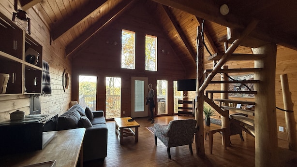 Un ampio soggiorno con soffitto in legno, una scala e grandi finestre.
