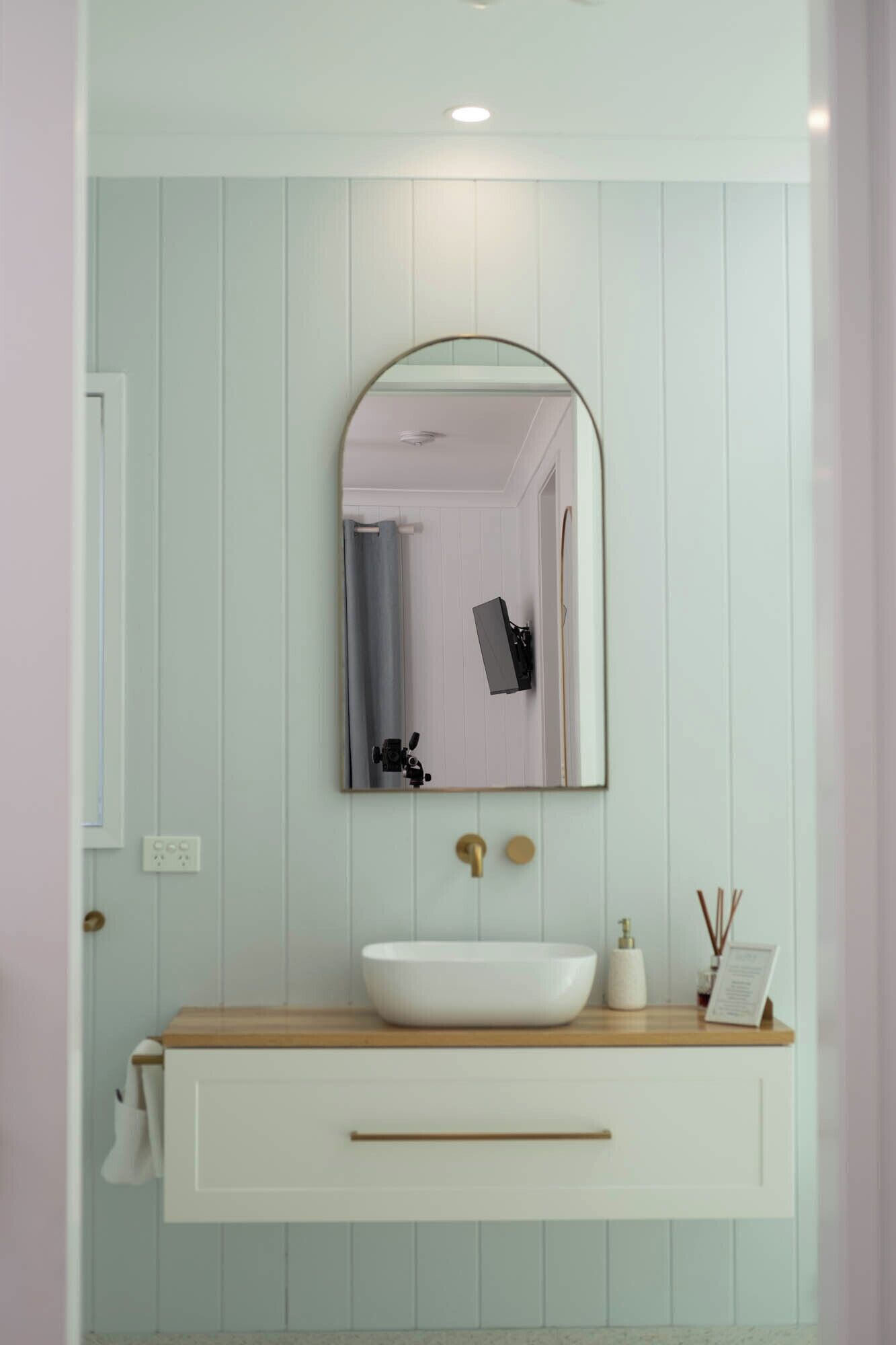A bathroom with a white vanity, a round mirror, and a white sink.