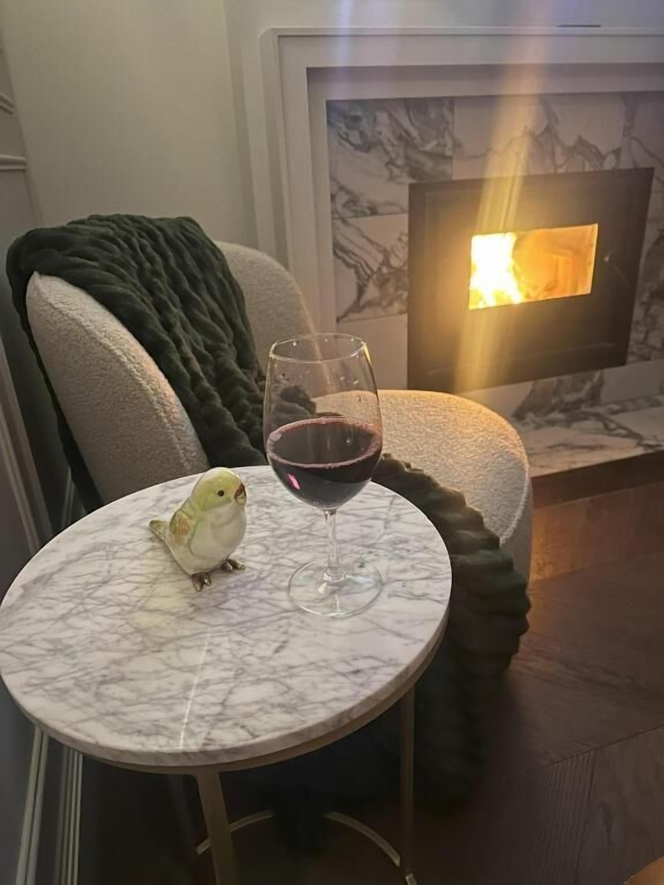 Ein kleiner runder Tisch mit Marmorplatte, ein Glas Rotwein und ein Vogel darauf.