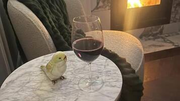 Ein kleiner runder Tisch mit Marmorplatte, ein Glas Rotwein und ein Vogel darauf.