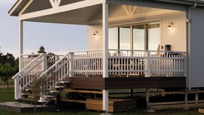 A modern house with a covered porch, a staircase, and a fire pit in the yard. - Lusso Retreats (Moffatdale)