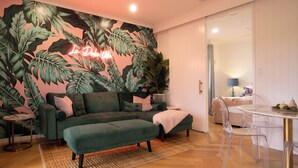 A cozy living room with a green sofa, a small round table, and a neon sign on the wall. - Lusso Retreats (Moffatdale)