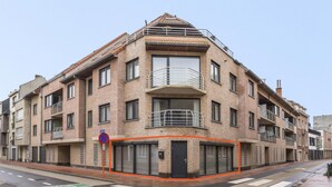 En bygning med flere etager, facade i mursten, altaner og en port.
