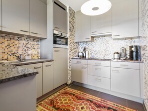A modern kitchen with white cabinets, a built-in oven, and a coffee maker. - Attractive apartment with dunes view (Blankenberge)