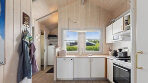 Una cocina moderna con armarios blancos, horno empotrado y ventana con vista a zonas verdes.