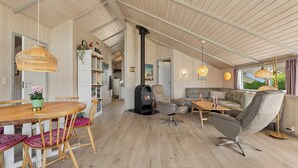 Amplia sala de estar con techo de madera, chimenea, sofá y mesa de comedor con sillas.