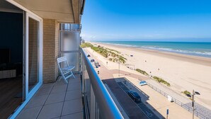 Un balcon avec vue sur la plage et un espace de stationnement.