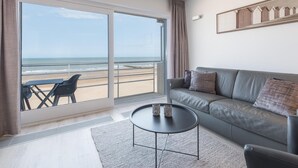 A modern living room with a large sliding glass door leading to a balcony overlooking the beach. - Studio on the 4th floor with sea view (Middelkerke)
