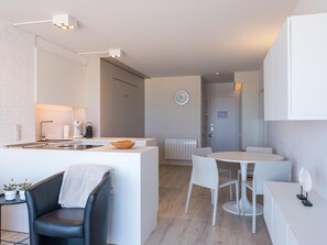 Une cuisine moderne dotée d’un îlot central, de meubles blancs et d’un coin repas avec une table ronde et des chaises.