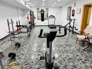 Ett gym med olika typer av träningsredskap, en boxningssäck och en stol.