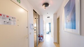 A hallway with a fire extinguisher, emergency exit sign, and a framed picture on the wall. - Beautiful apartment on the 4th floor with garage (Middelkerke)