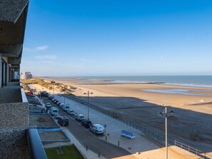 A coastal road with parked cars, a pedestrian walkway, and a beach in the background. - Beautiful apartment on the 4th floor with garage (Middelkerke)