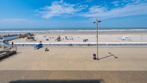 Eine Strandpromenade mit freiem Blick auf das Meer, einem Sandstrand und einem befestigten Gehweg.