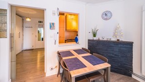 Een moderne keuken met een inbouwoven, een eethoek met een houten tafel en stoelen, en een zwart stenen haard.