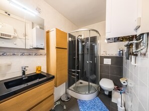 A modern bathroom with a glass-enclosed shower, a toilet, and a sink with a black countertop. - Spacious studio with separate sleeping area (Middelkerke)