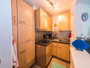 Une cuisine de taille réduite, avec des meubles de rangement en bois, une cuisinière et un évier.