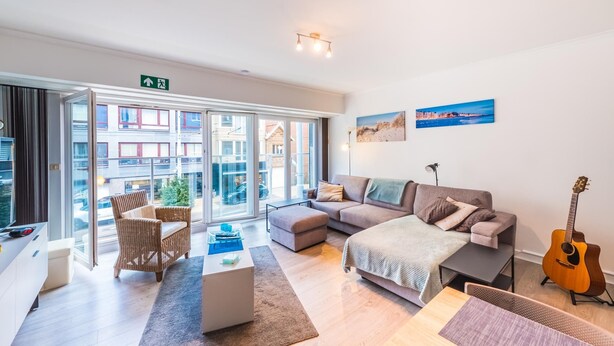 Een moderne woonkamer met een bank, een salontafel en een gitaar.