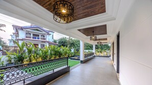 A covered corridor with a railing, potted plants, and hanging lights. - ELIVAAS Valley View 5BHK Villa With Pool (Mapusa)