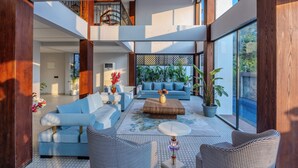 A spacious living area with a modern design, featuring a large sofa, a coffee table, and a staircase leading to an upper level. - ELIVAAS Valley View 5BHK Villa With Pool (Mapusa)