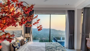 A modern hotel room with a large bed, a view of the city, and a balcony. - ELIVAAS Valley View 5BHK Villa With Pool (Mapusa)