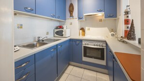 A compact kitchen with blue cabinets, a microwave, a sink, and a stove. - Retro studio with sleeping area (Middelkerke)