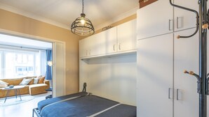 A modern bedroom with a bed, wardrobe, and a view of the outside. - Retro studio with sleeping area (Middelkerke)