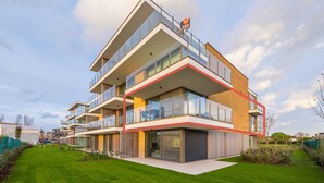 A modern multi-story residential building with balconies, large windows, and a well-maintained lawn. - Spacious apartment with sunny terrace (Middelkerke)