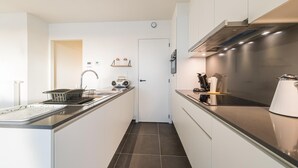 A modern kitchen with a central island, stainless steel appliances, and a sleek backsplash. - Spacious apartment with sunny terrace (Middelkerke)