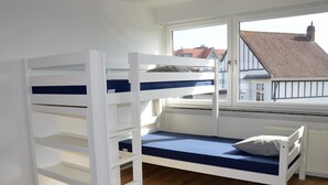 A bunk bed with a window view of a red-tiled roof building. - Luxury holiday home by the sea (Middelkerke)