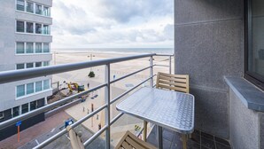 Un balcon avec une table et des chaises donnant sur une plage et un chantier de construction.