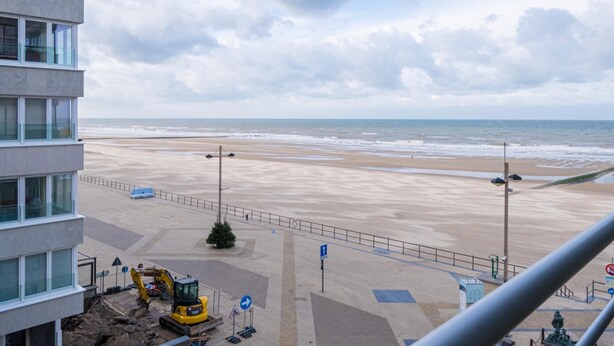 Une vue sur la plage depuis un immeuble de grande hauteur, avec du matériel de construction visible sur le sable.