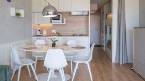 Een moderne keuken met witte kasten, een eettafel met witte stoelen en een hanglamp.