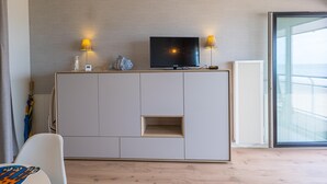 Een moderne woonkamer met een televisie op een kast, twee lampen en een groot raam.