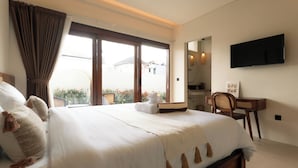 Habitación de hotel con una cama grande, un escritorio, un televisor y vistas al exterior.