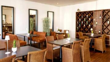 Een moderne hotelentree met rieten meubels, een wijnkelder en grote spiegels.