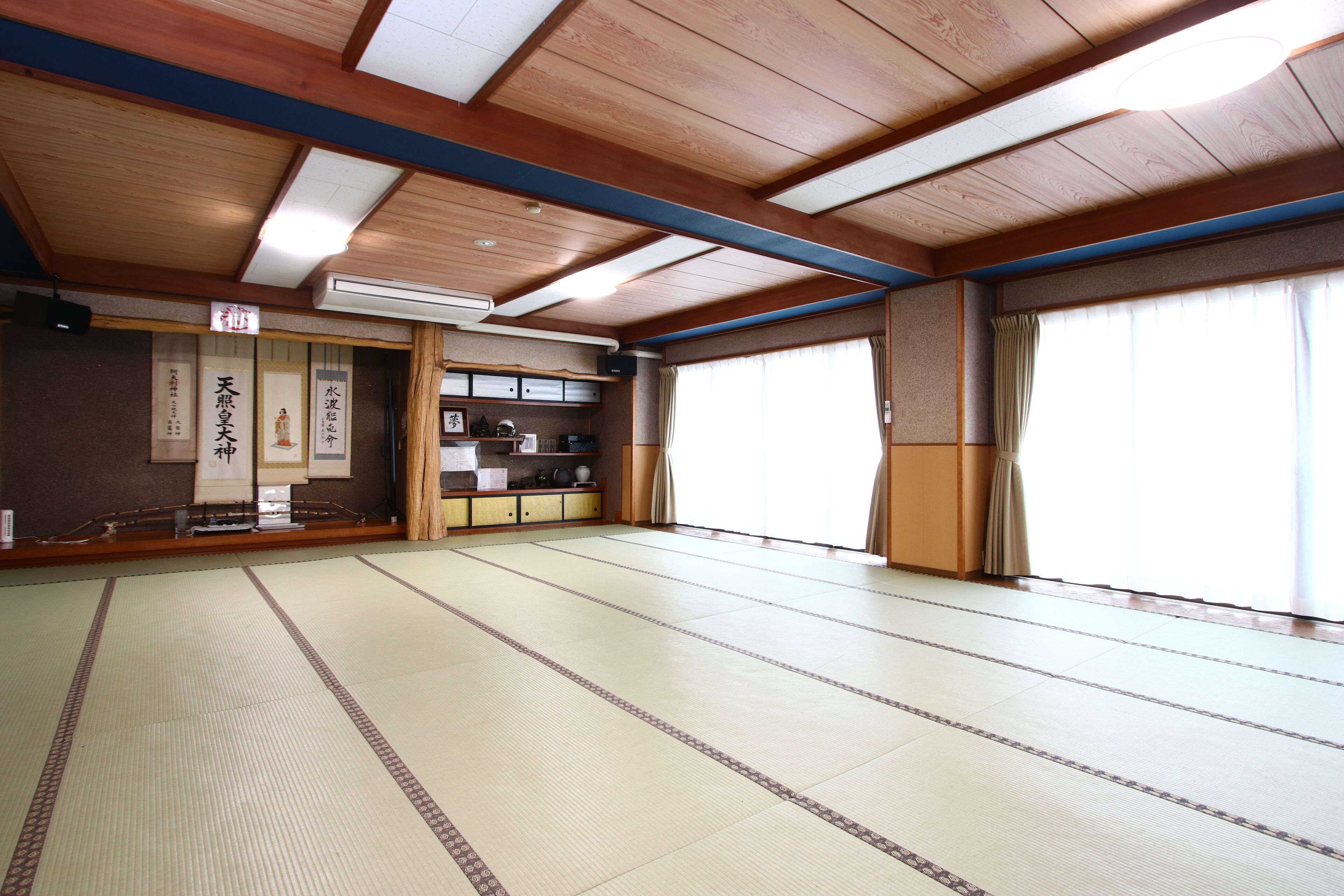 Una habitación japonesa tradicional con suelo de tatami, vigas de madera y puertas correderas.