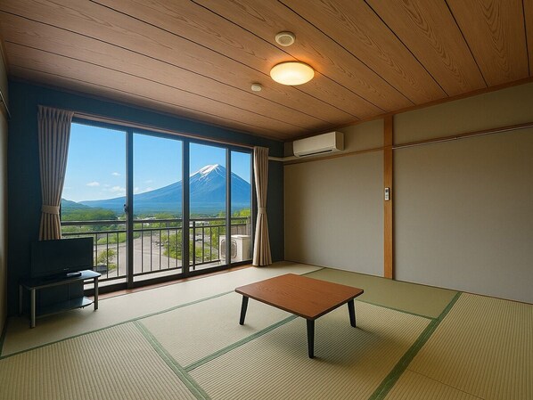 Una habitación con suelo de tatami, televisor, una mesita y un amplio ventanal con vistas a la montaña.