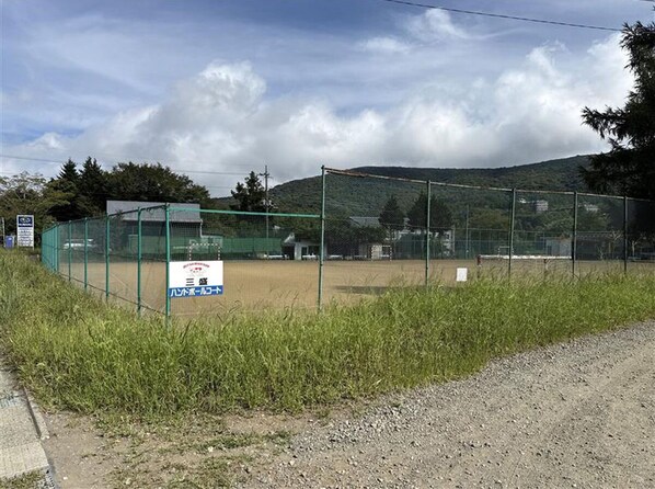 Un terrain de sport clôturé, avec un panneau indiquant qu’il s’agit d’un terrain de baseball.