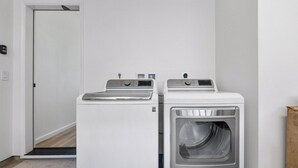 A laundry room with two white washing machines and a dryer. - Marbella Lane - 7BR Home w Mountain Ocean Views (Waianae)