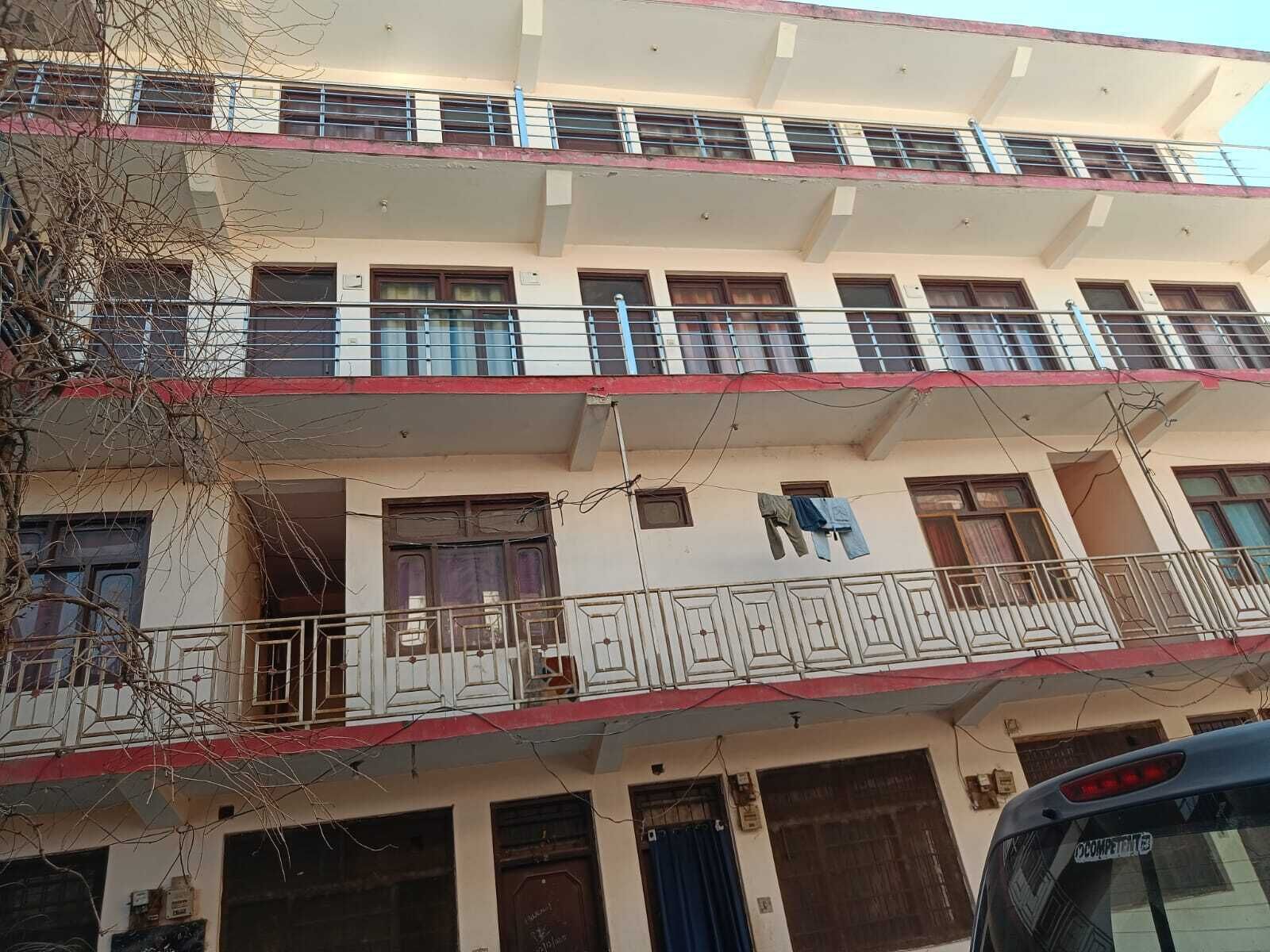 Un edificio de varios pisos con balcones, ventanas y un coche a la vista.